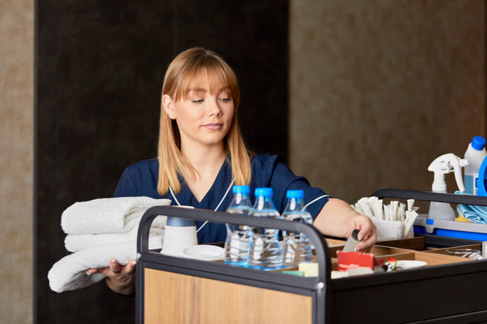 Glanz & Glorie Hotel Service – erfahrene Reinigungskraft bei der Vorbereitung des Reinigungswagens