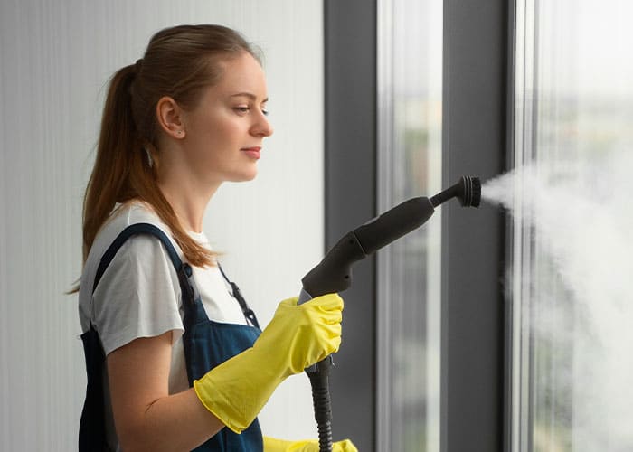 Mitarbeiterin der Glanz & Glorie Hotel Service bei der professionellen Glasreinigung mit Dampfreiniger – streifenfreie Sauberkeit für Hotelfenster