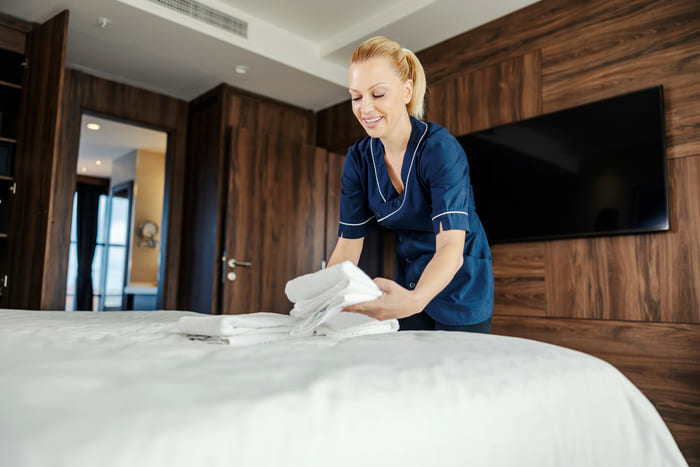 Zimmermädchen richtet Handtücher auf dem Bett als Teil des Turndown-Services – Glanz & Glorie Hotel Service