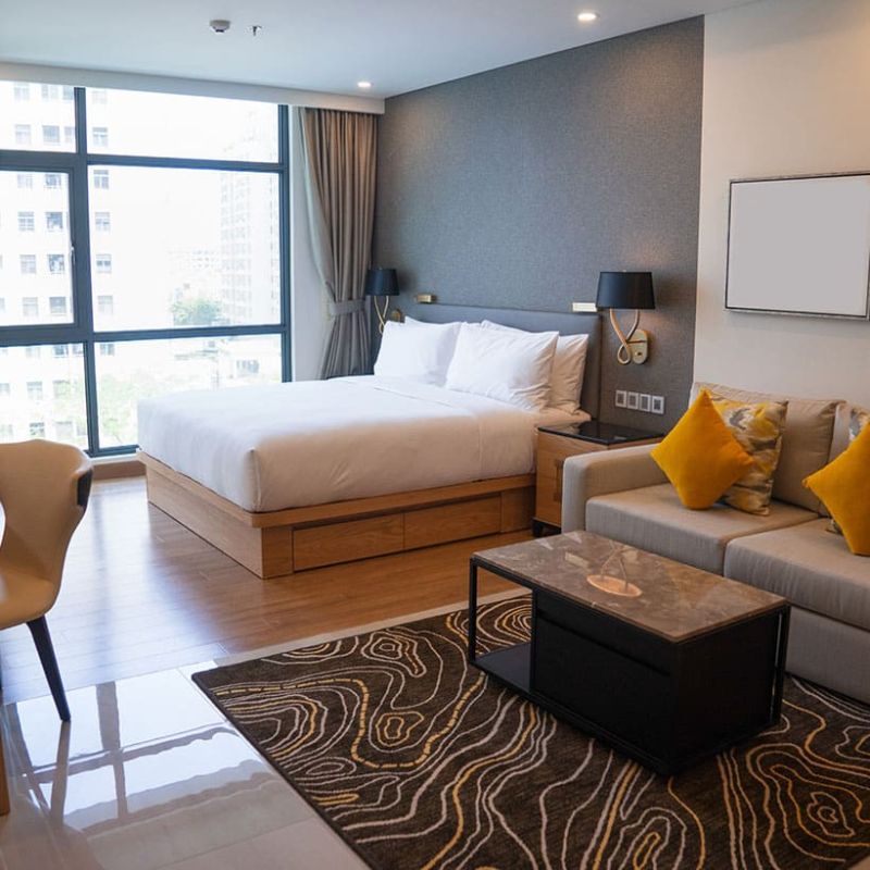 Modernes, sauberes Hotelzimmer mit Doppelbett, Sofa und großem Fenster – professionell gereinigt für höchsten Gästekomfort